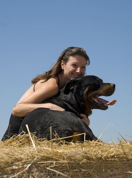 smiling young woman and her big black dog purebred rottweiler