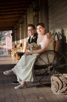 Happy same sex couple in wedding on antique bench
