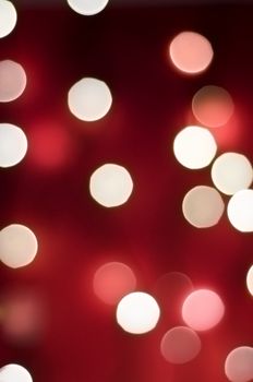 Bokeh lights with rich red background blending into darkness, portrait orientation.