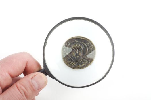 magnifying glass and fake ancient coins over white