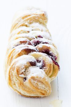Close up pastry with cherry jam filling and sugar powder on white wooden table