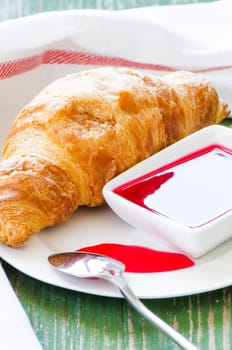 Croissant with jem on wooden table