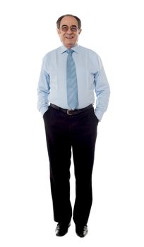 Matured businessman posing with arms in his pocket, looking at camera