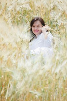 Young sexy woman lying in a field of rye, happy, smiling and having fun.