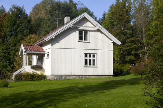 White summer cottage surrounded by trees in Norway