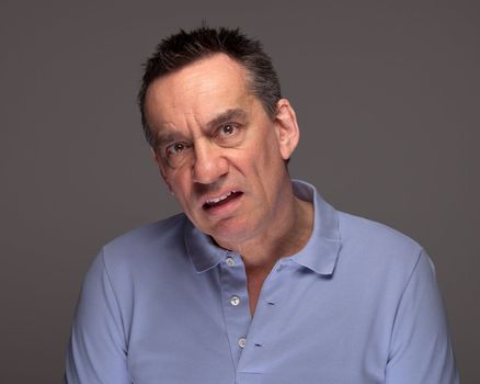 Middle Age Man Pulling Unhappy Face and Grimacing on Grey Background