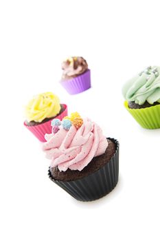 Scattered colourful cupcakes. Over a white background