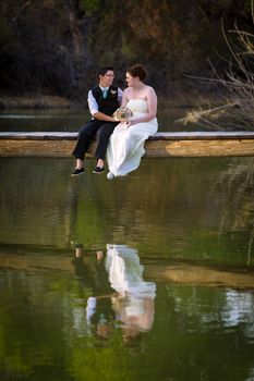 Affectionate lesbian couple sitting on dock above lake