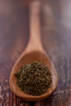 parsley spice in wooden spoon over wood background - selective focus