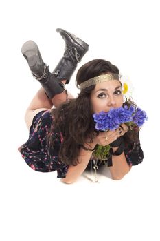 Young hippie girl with bunch of flowers posing to the camera