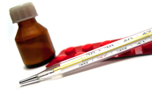 Medicine bottle, tablets and thermometer on white