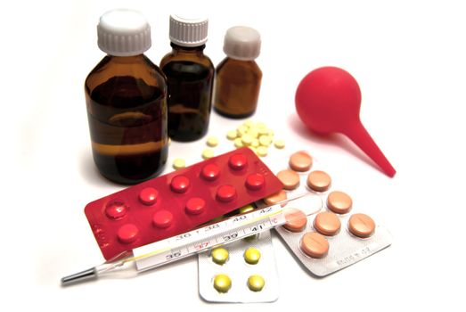 Pills, bottles, enema and thermometer on white background