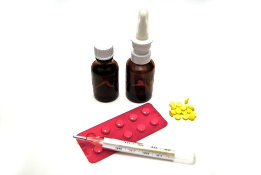 Pills, bottles, and thermometer on white background