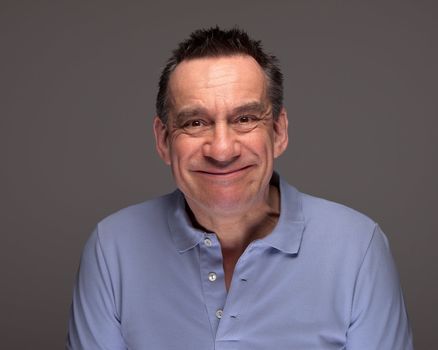 Handsome Middle Age Man Pulling Silly Face Grinning on Grey Background