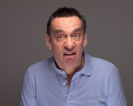 Middle Age Man Pulling Funny Grimace Face on Grey Background