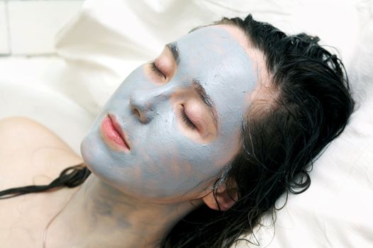 A nice woman putting a mud mask on her face
