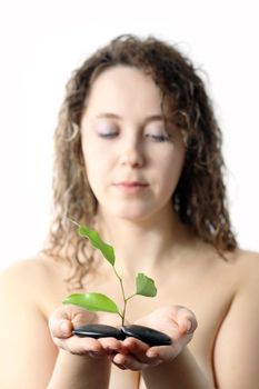 Stock photo: an image of a girl with plant and stones in her hands