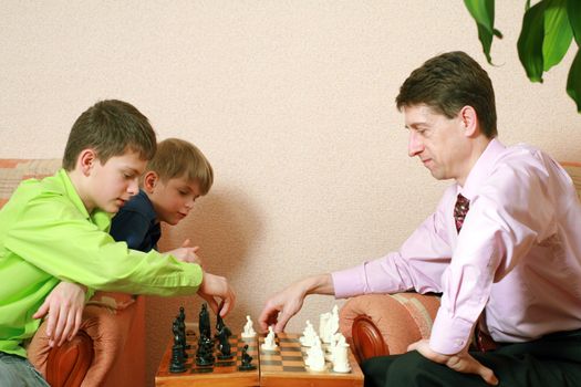 A father and his sons playing chess