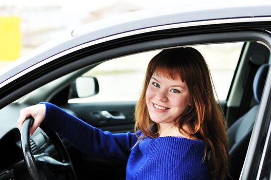 pretty redheaded happy teen girl driving a car 