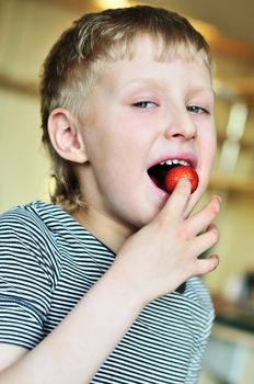 little funny boy is enjoying strawberry