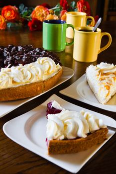 Different Dutch pastry or Limburgian flans with cups, mugs and flowers prepared for a party - vertical