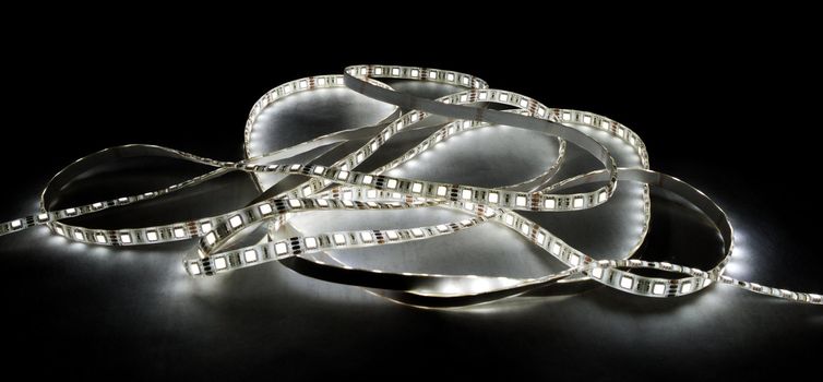 white led strip with a glue layer, background in the dark, illuminated by strip