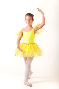 Smiling little ballerina exercising, studio shot on white background 