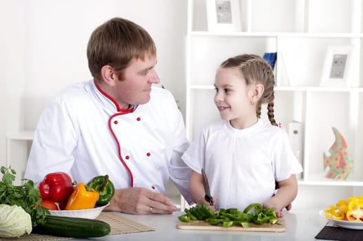 portrait of father and daughter cooking salad together in the kitchen