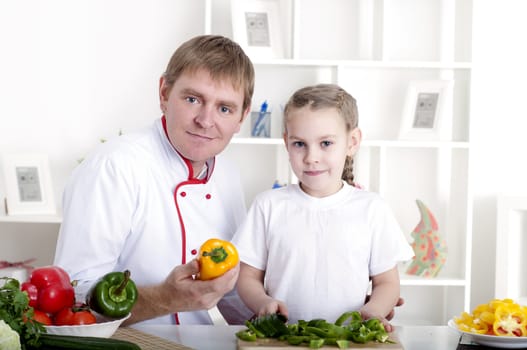 portrait of father and daughter cooking salad together in the kitchen