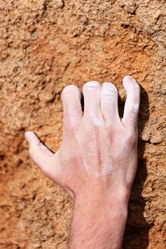 Climbing hand grip on rock. Male hand with chalk powder on rocks.