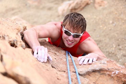 Climbing. Male climber rock climbing cliff wall with climb rope. Strong man climber on the way to summit at success.