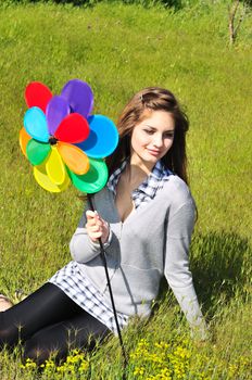 girl with windmill sitting in the grass 
