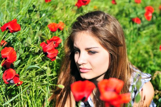 beautiful girl with long hair relaxing in the poppy field 