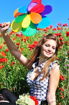 girl with windmill sitting in the poppy field