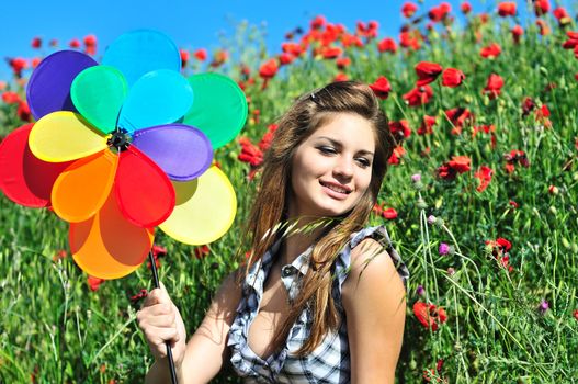 cute teen girl having fun with windmill on the poppy field