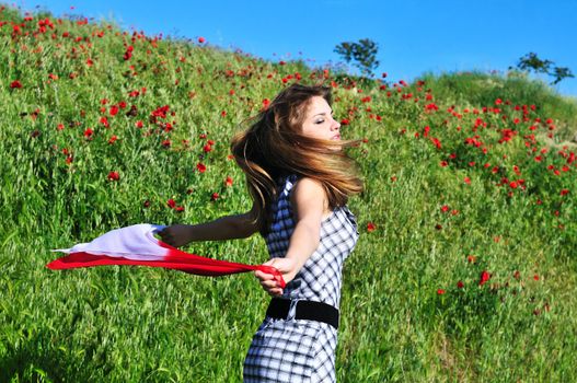 teen girl dancing in field and holding red scarf 