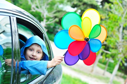 boy in the car holding windmill and smiling 