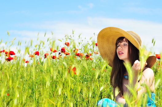 longhaired girl wearing straw hat relaxing in field 