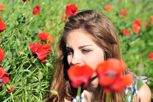 beautiful girl with long hair relaxing in the poppy field