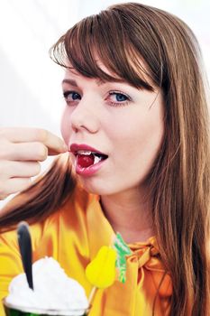Young beautiful woman eating cherry and dessert in cafe 
