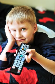 boy watching tv, laying in bad and making face