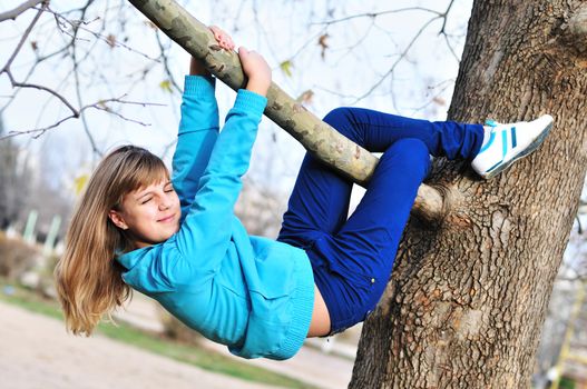 Teen girl hanging on the tree in autumn time, like a sloth. 