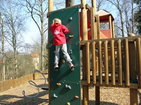 Photo of a blonde girl who plays on a playground.