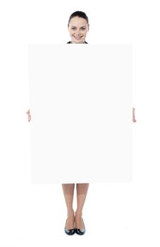 Portrait of a happy young woman holding blank billboard against white background