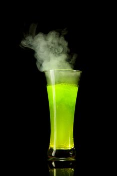 Boiling radioactive green alcohol with smoke, studio shot isolated on black background 