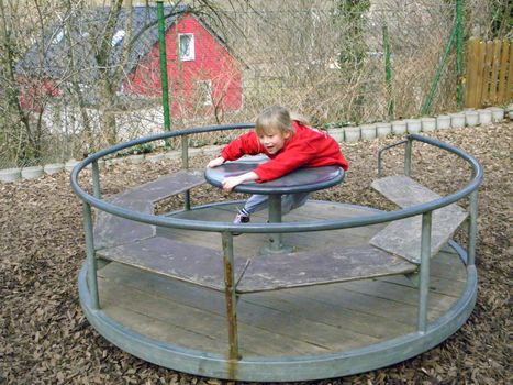 Photo of a blonde girl who plays on a playground.