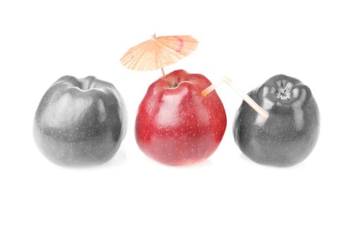 Two colourless red apples and one apple with cocktail tube and umbrella.