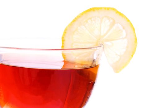 Brim of transparent cup with black tea and segment of a lemon on white background. Focus on right side of the cup.