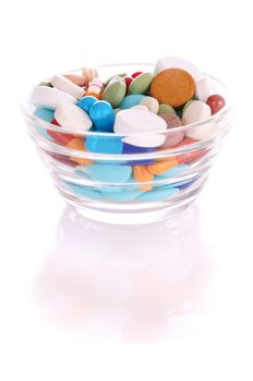 Transparent saucer with many-colored pills with reflection