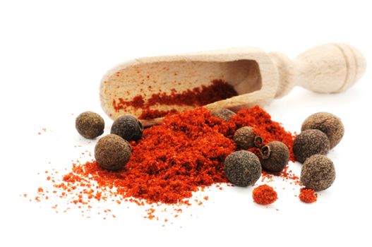 Wooden scoop in heap of pepper with peppercorns of sweet pepper